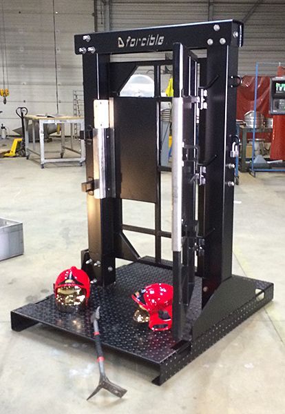 Portail de sécurité en métal noir dans un atelier, avec casques et outil sur la base.