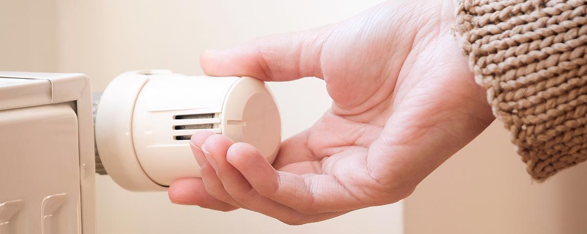 Focus sur une main réglant le thermostat d'un radiateur