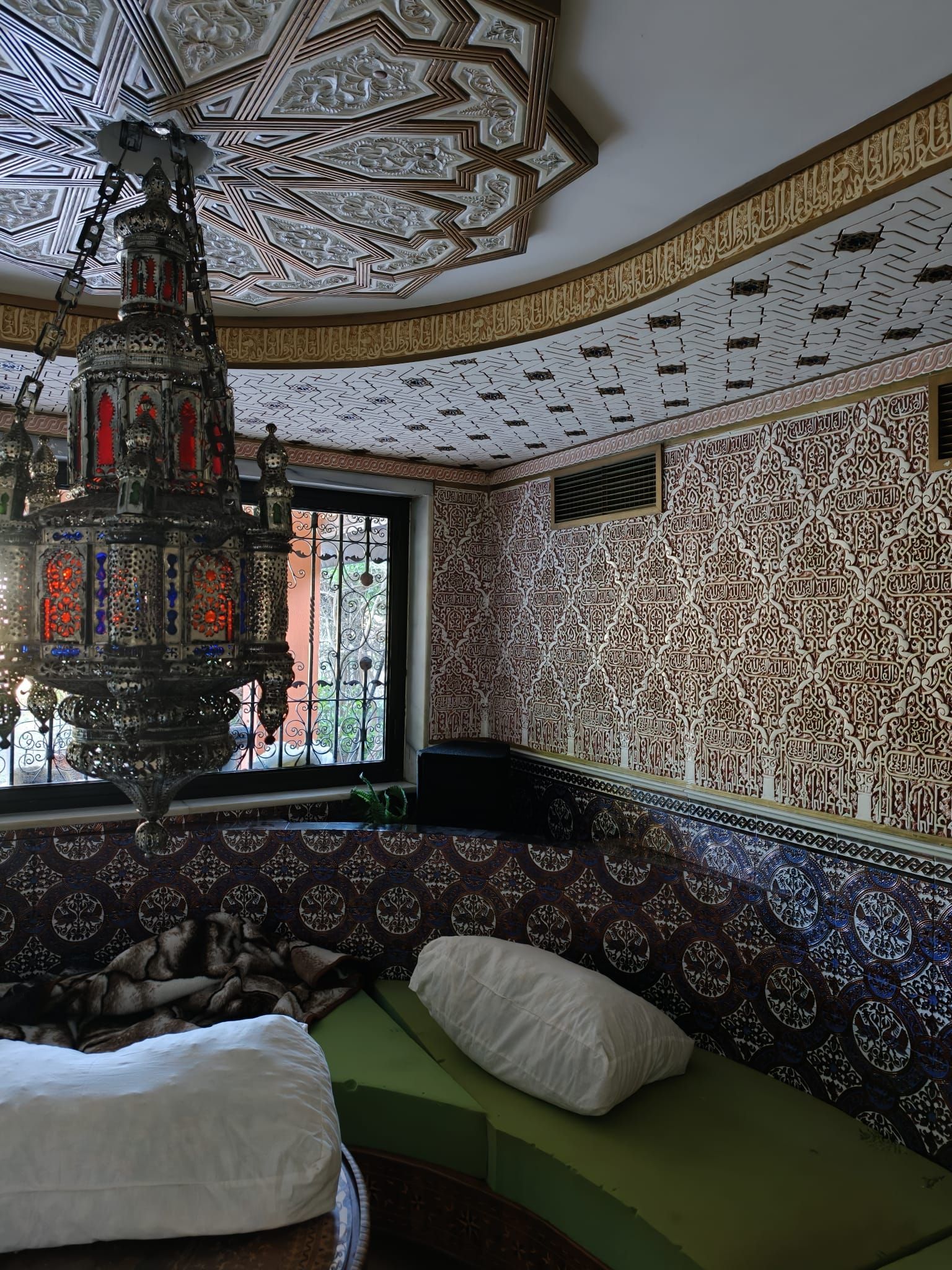 Habitación con azulejos de mosaico, una elaborada lámpara colgante, techo decorado