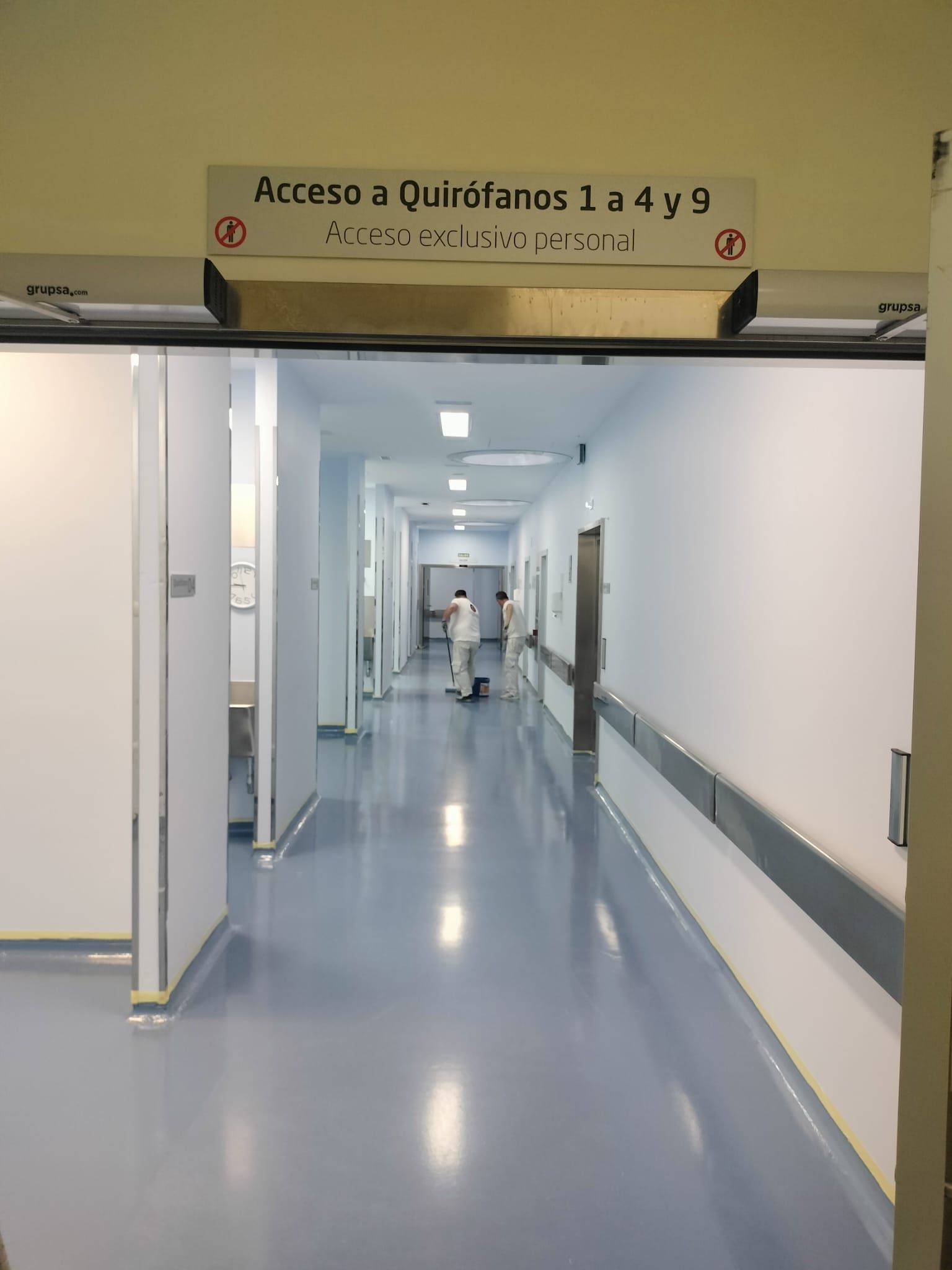 Pasillo del hospital con puertas dobles abiertas y un letrero sobre la entrada.