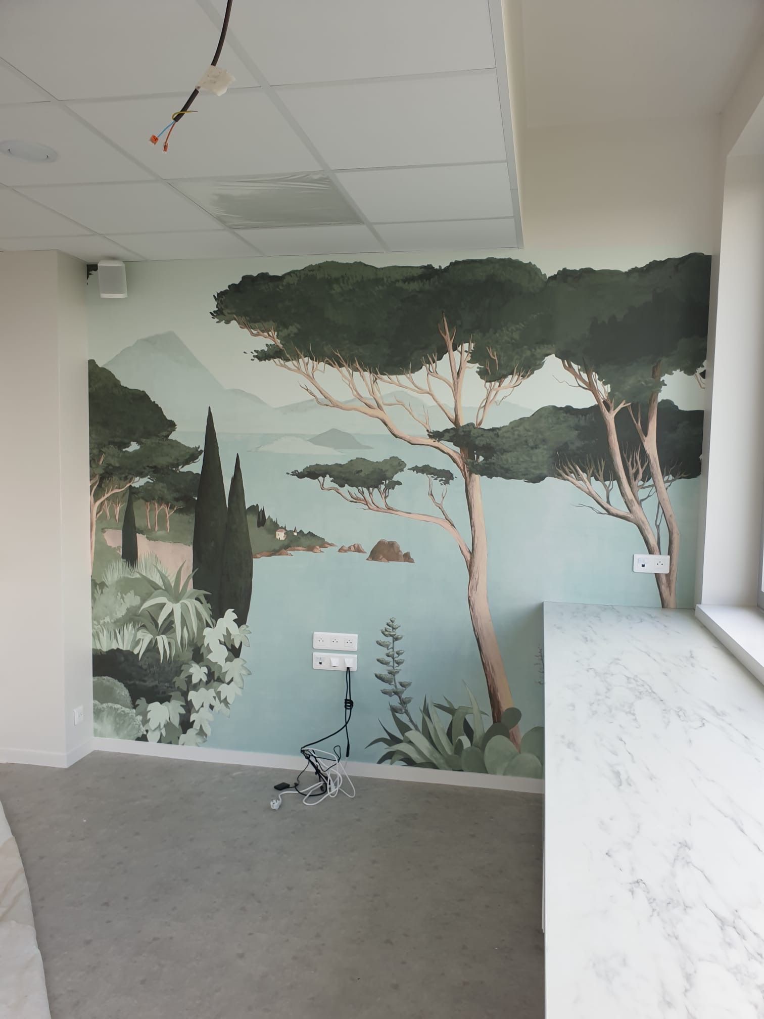 Pièce en rénovation avec un papier peint représentant une île avec des arbres