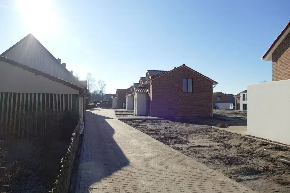 Sonnige Wohnstraße mit neu gebauten Backsteinhäusern und einer im Bau befindlichen gepflasterten Straße