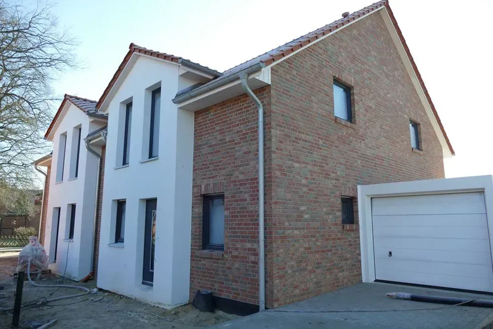 Zweistöckiges Haus aus Backstein und Weiß mit Garage im Tageslicht