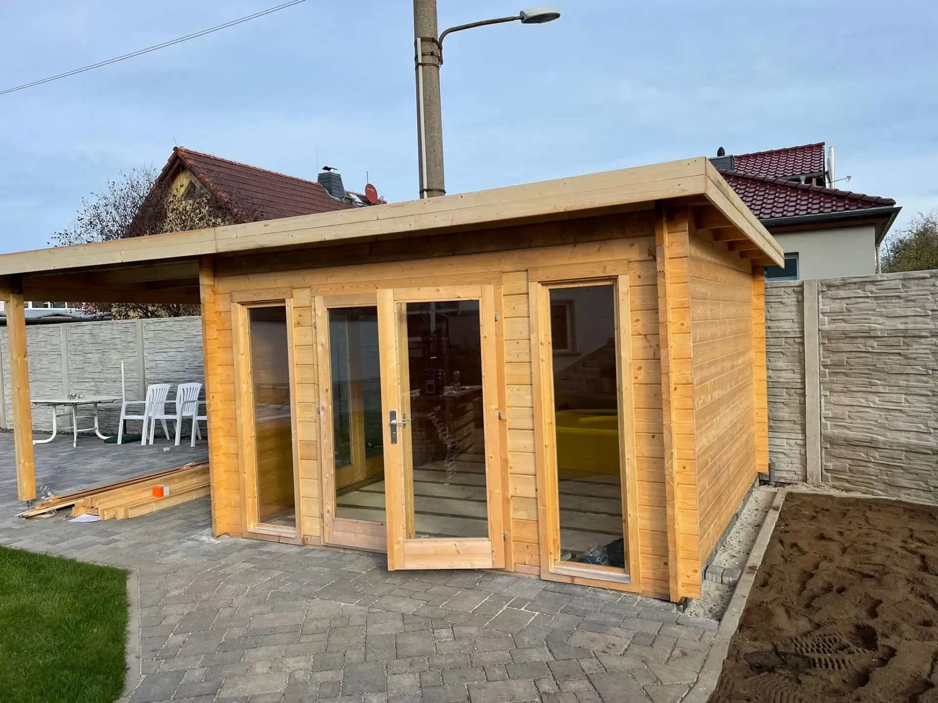 Referenzbild: Gartenhütte aus Holz mit ebenerdigen Fenstern und Flügeltür