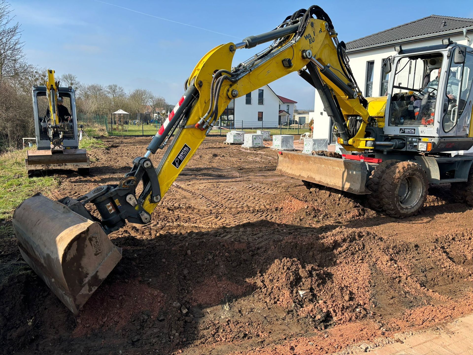 Referenzbild: Ein gelber Bagger bewegt Erde auf einer Baustelle.