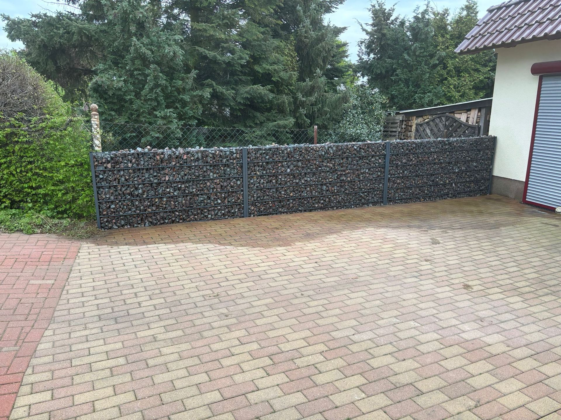 Referenzbild: Eine gepflasterte Auffahrt mit einem Zaun und einer Garage im Hintergrund.