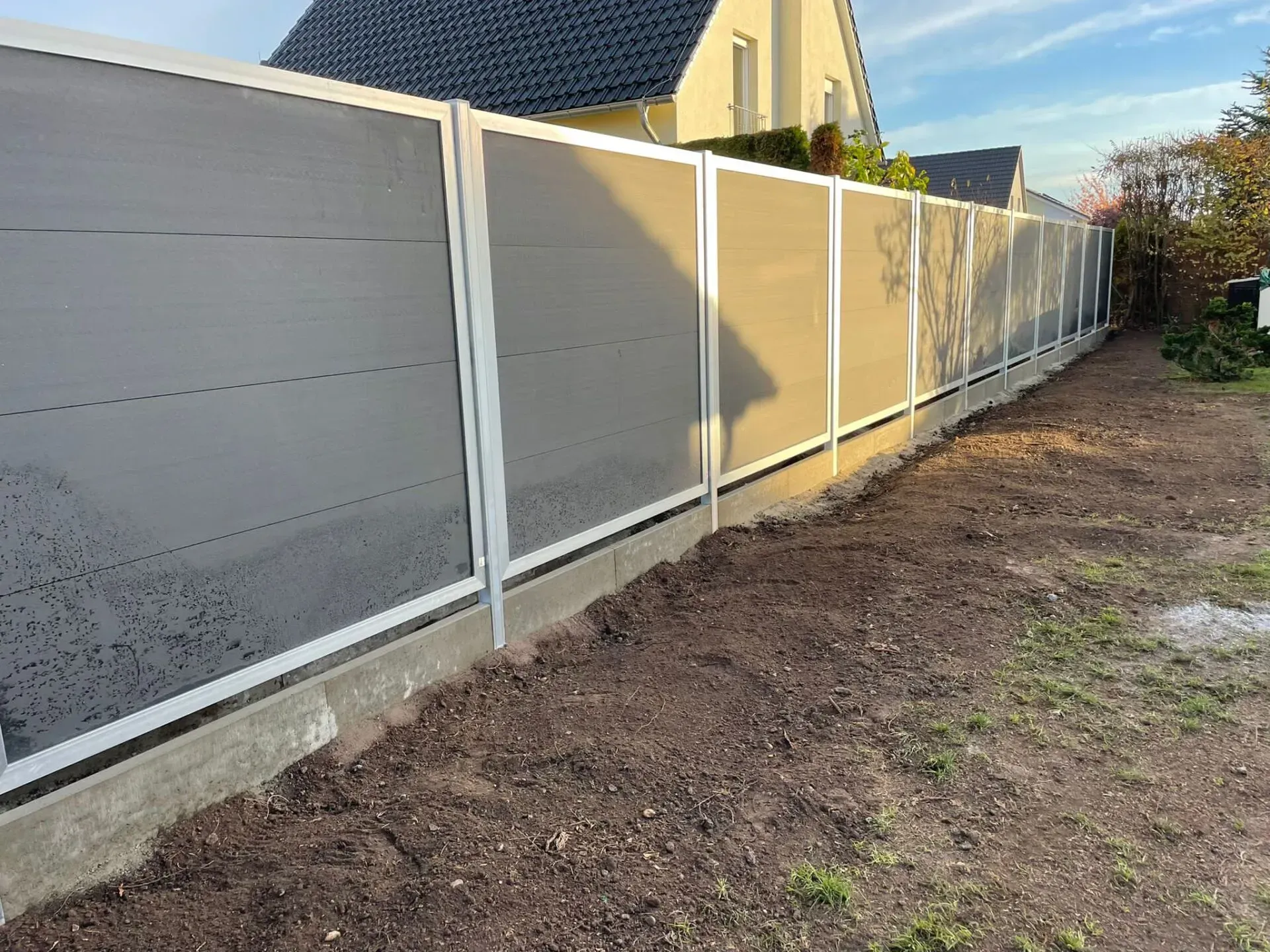 Referenzbild: Gartenzaun aus silbernen Metall inklusive Sichtschutz in grauer Holzoptik