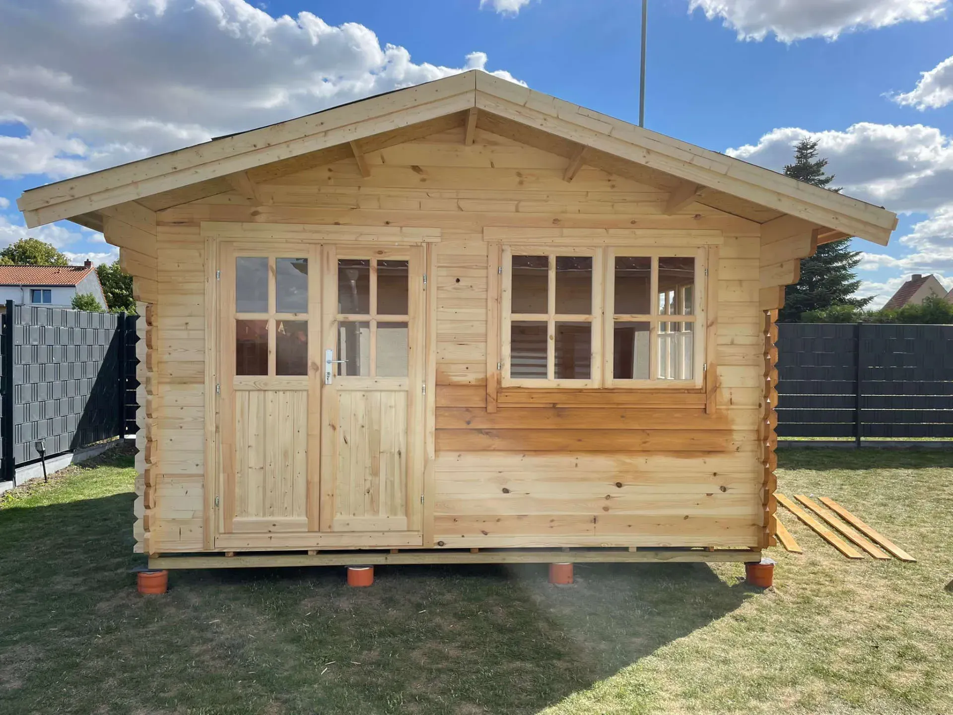 Referenzbild: kleine Gartenblockhütte aus Holz mit Sprossenfenstern und Türen