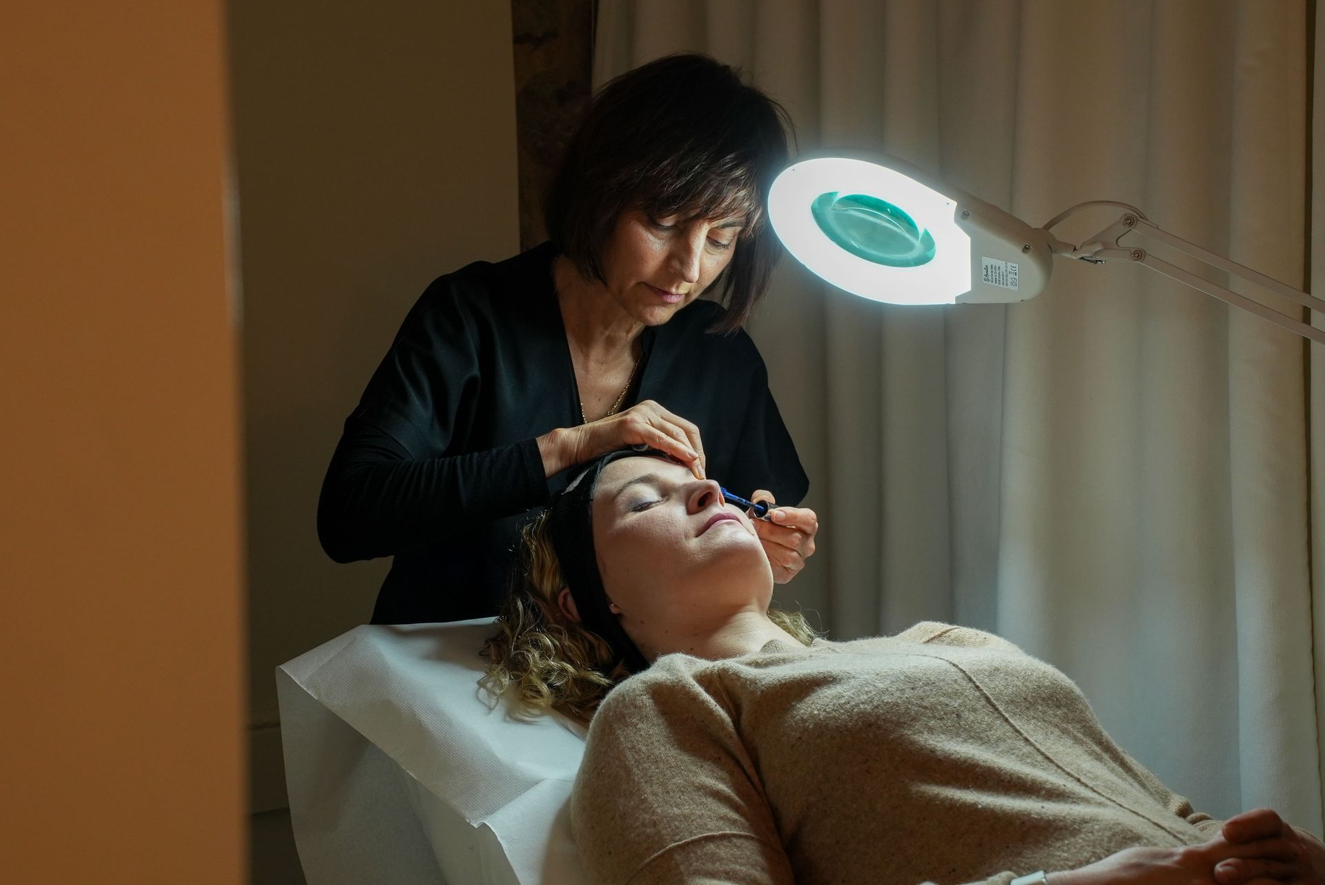 Esthéticienne en train de réaliser un maquillage sous une lumière