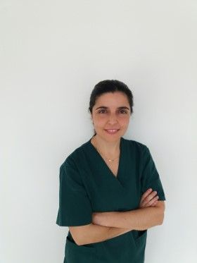 Una mujer con un matorral verde posa para una fotografía con los brazos cruzados.