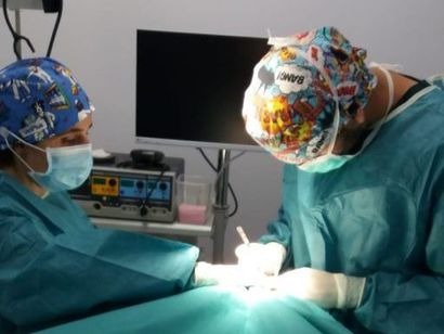 Un hombre con un uniforme azul señala una pantalla de computadora.