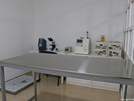 Una mesa de acero inoxidable en una habitación con un microscopio y otros equipos.
