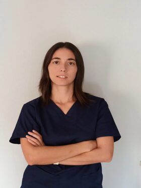 Una mujer con una blusa azul está de pie con los brazos cruzados.