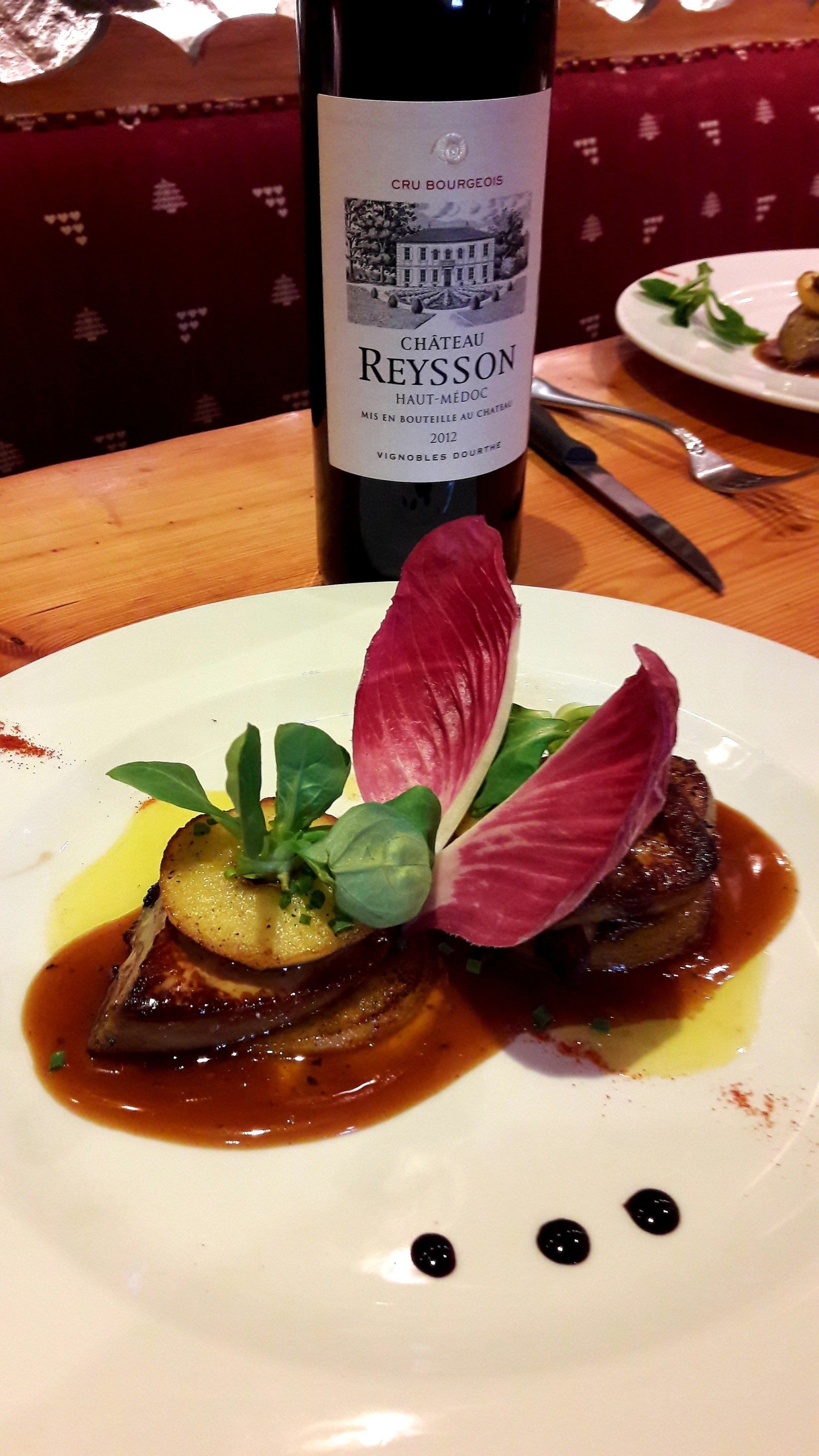 Plat de viande en sauce avec bouteille de Château Reysson