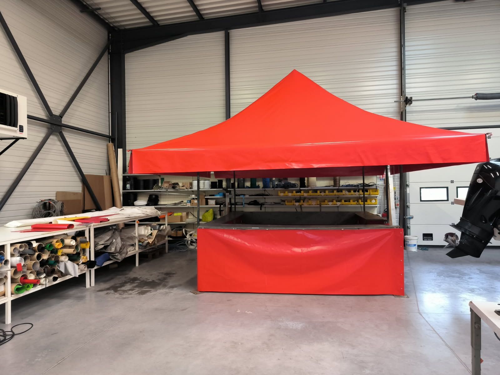 Une tente rouge à auvent a été installée à l'intérieur d'un atelier.