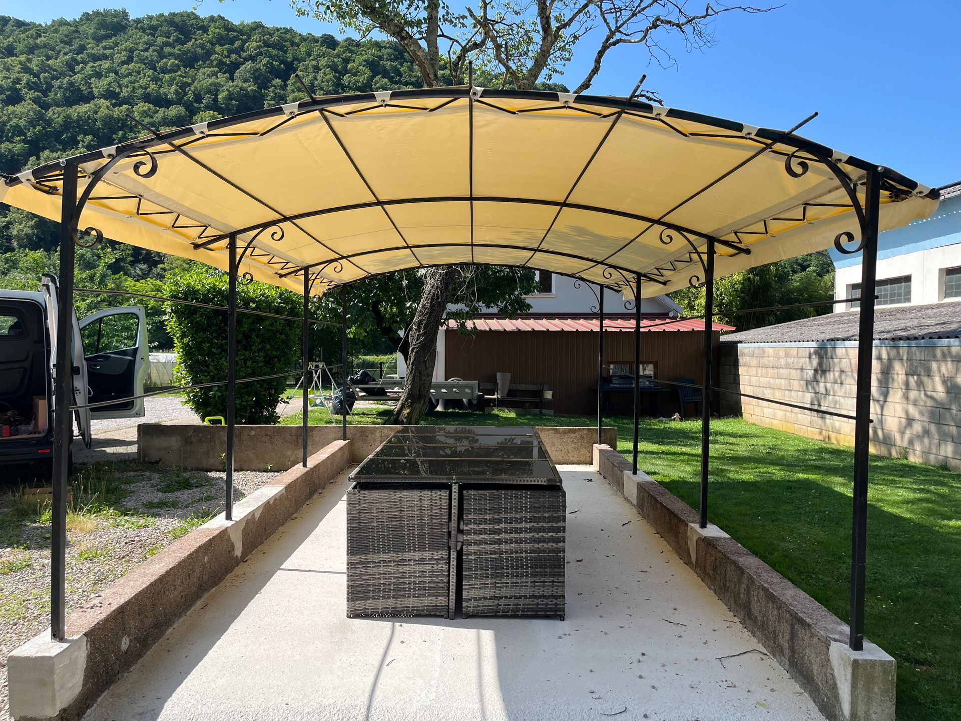 Auvent beige au-dessus d'une table à manger extérieure.