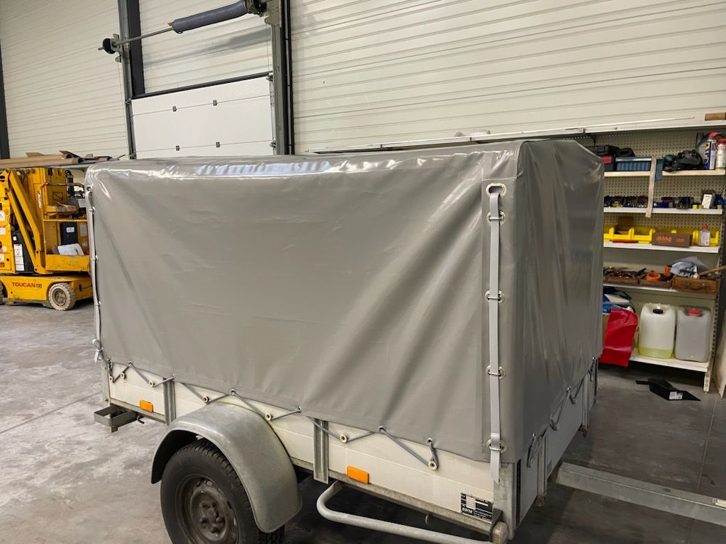 Remorque grise à roues, garée dans un garage.