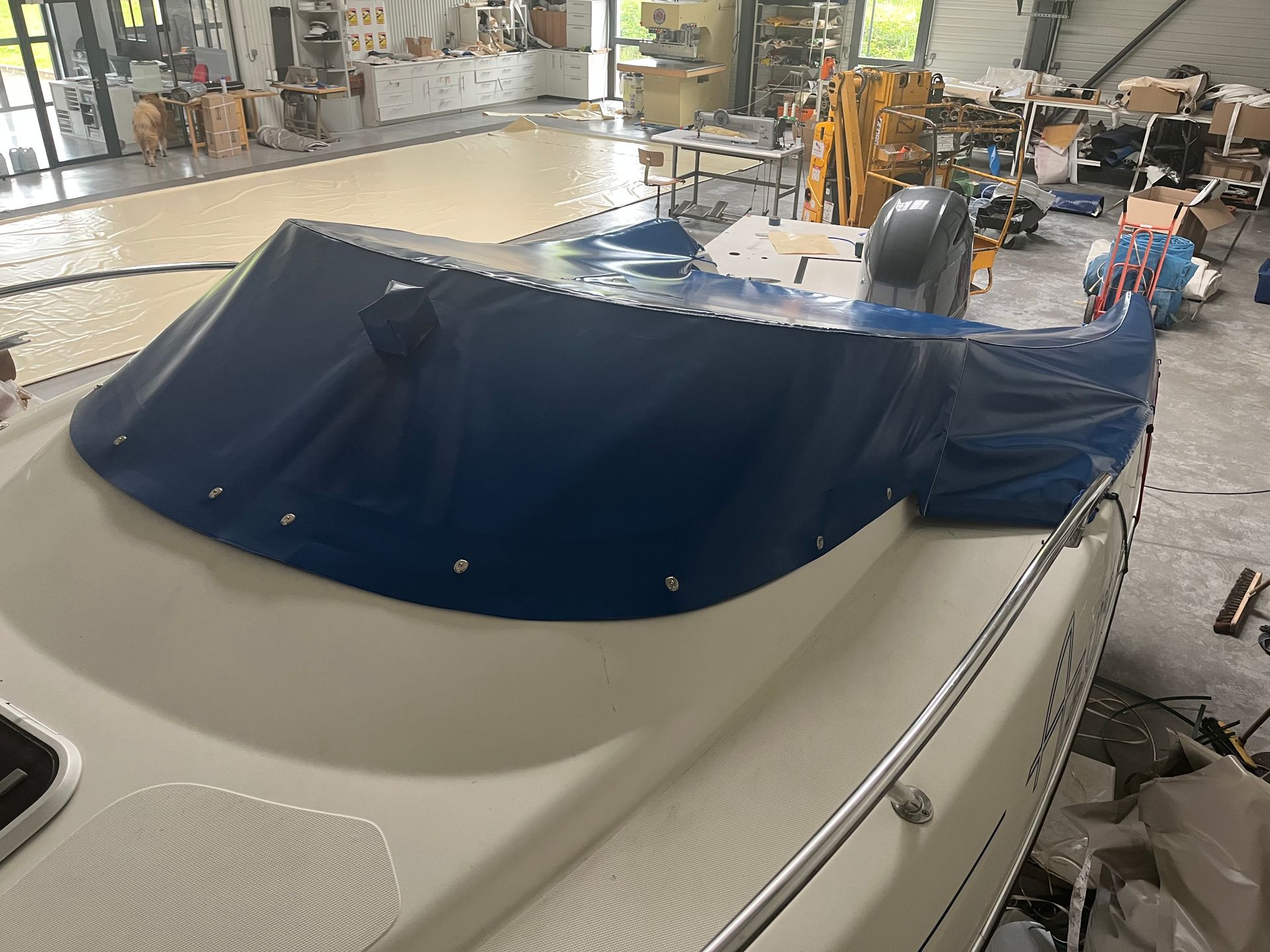 Intérieur d'un bateau recouvert d'une bâche bleue, dans un atelier.