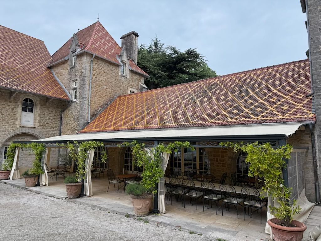 Terrasse couverte de tuiles, aménagée avec tables et chaises. 