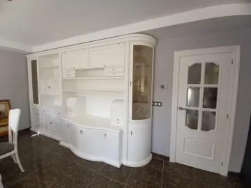 Mueble empotrado blanco con armarios y estantes en un comedor alicatado, junto a una puerta blanca