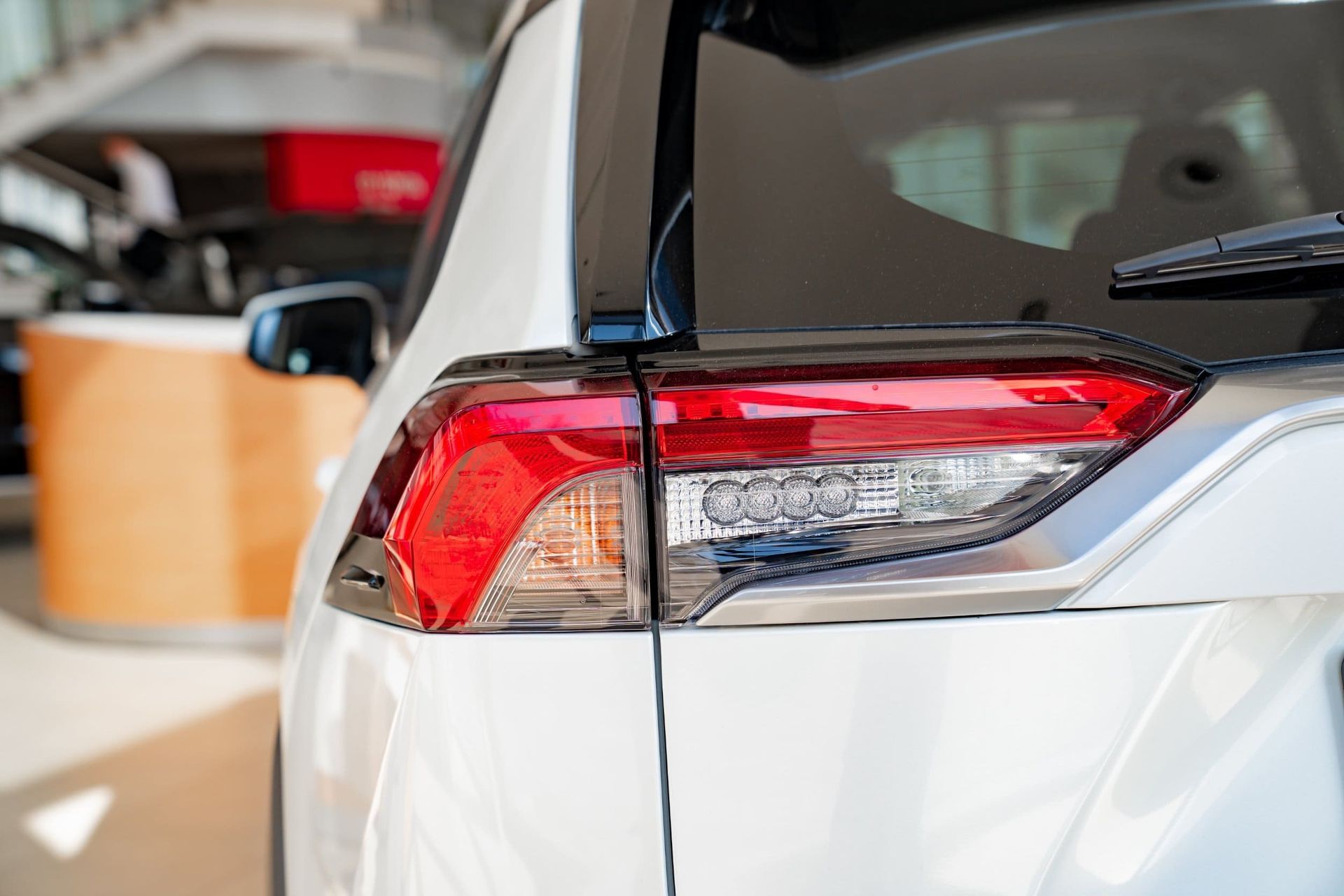 Primer plano de la parte trasera de un todoterreno blanco. Se aprecia el piloto trasero, con luces rojas y blancas, junto con una moldura negra y un limpiaparabrisas.