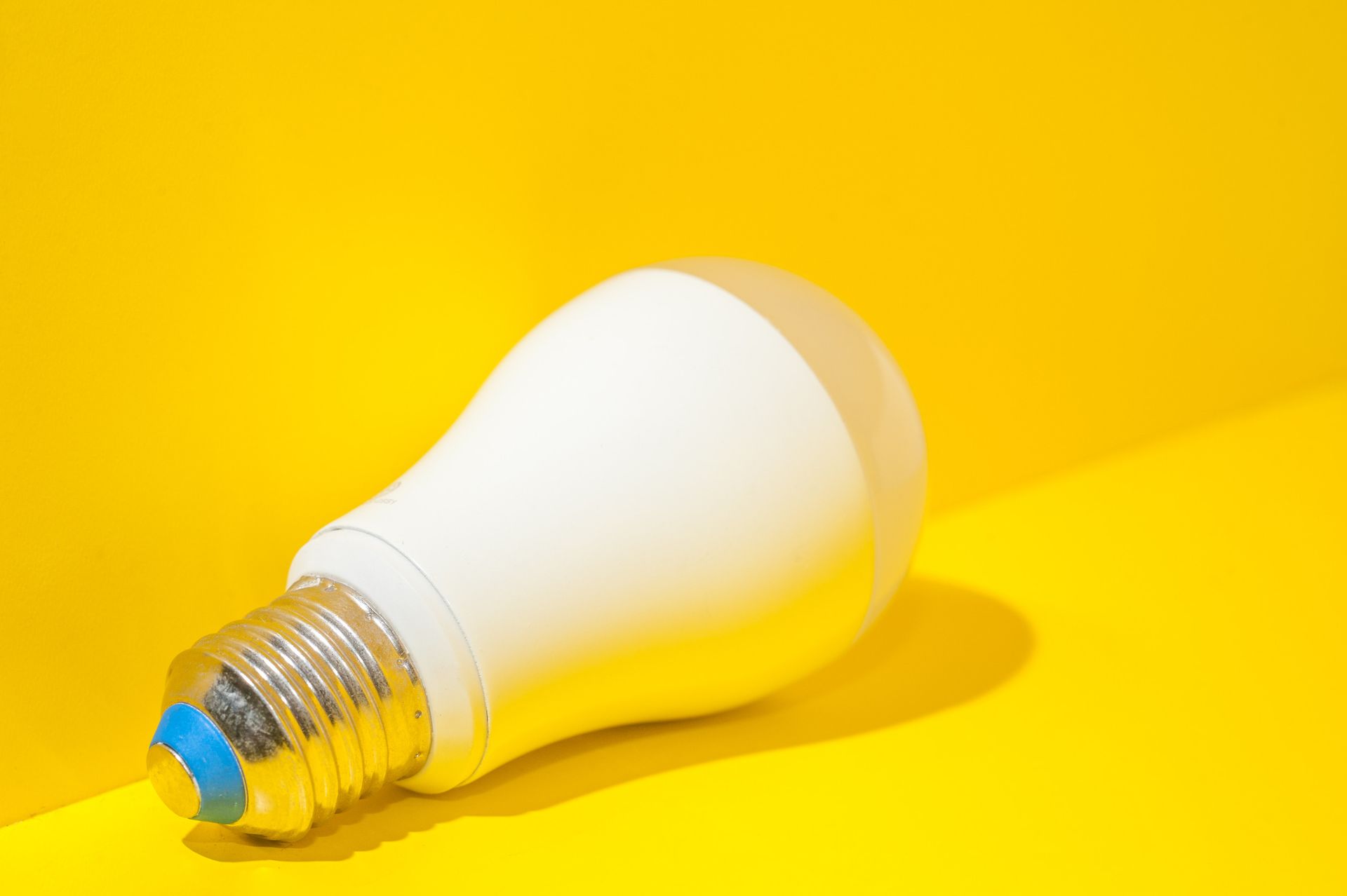 Una bombilla blanca está sobre una superficie amarilla.