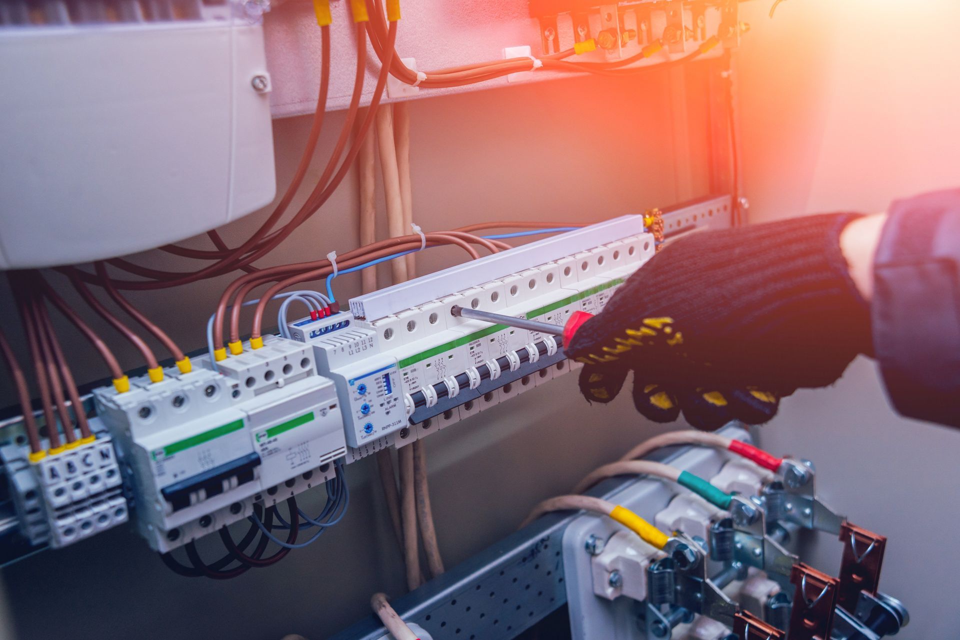 Una persona está trabajando en una caja eléctrica con un destornillador.