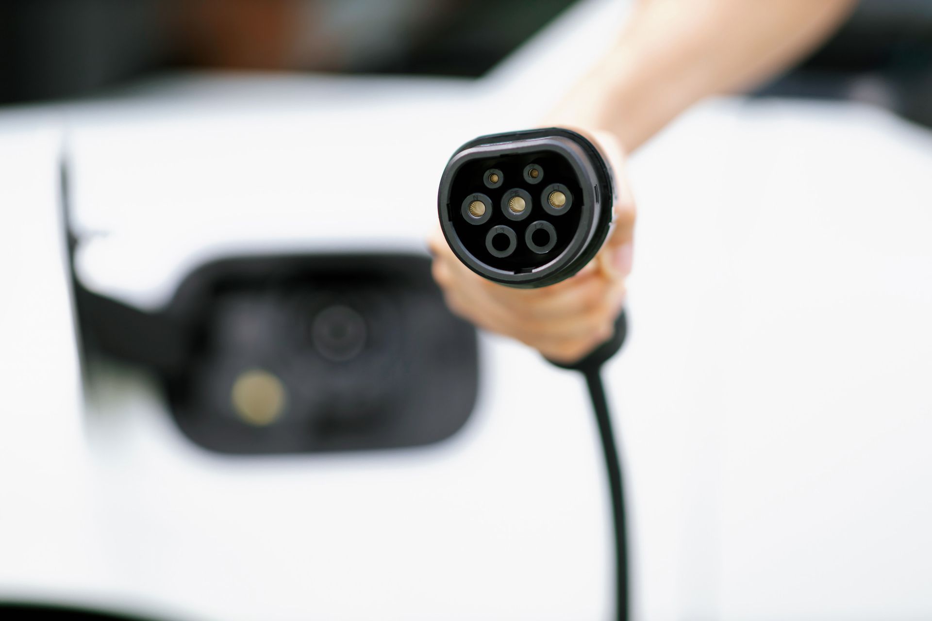 Una persona está cargando un coche eléctrico con un cable de carga.