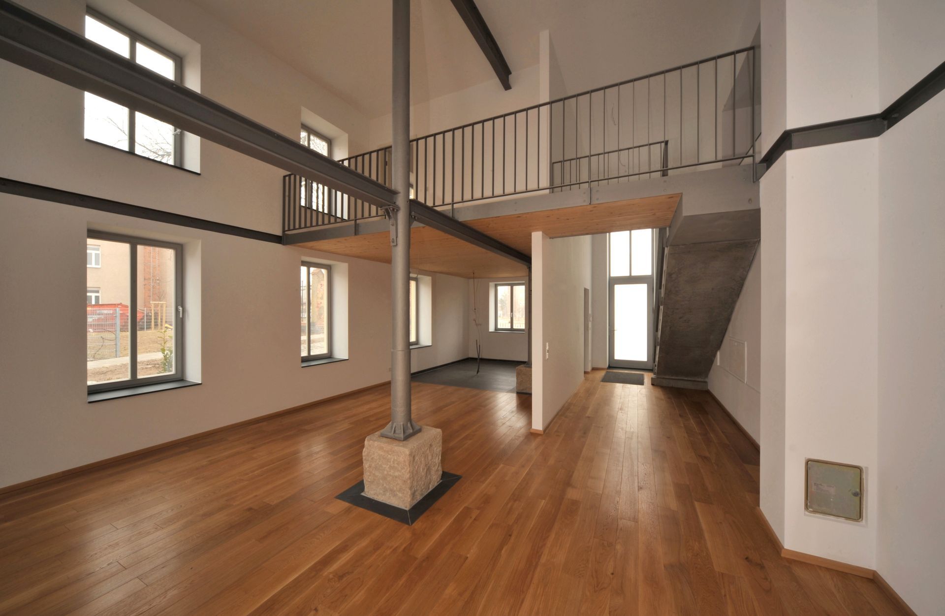 Geräumiges, offenes Loft mit Zwischengeschoss, Holzböden und Metallträgern; viel natürliches Licht.