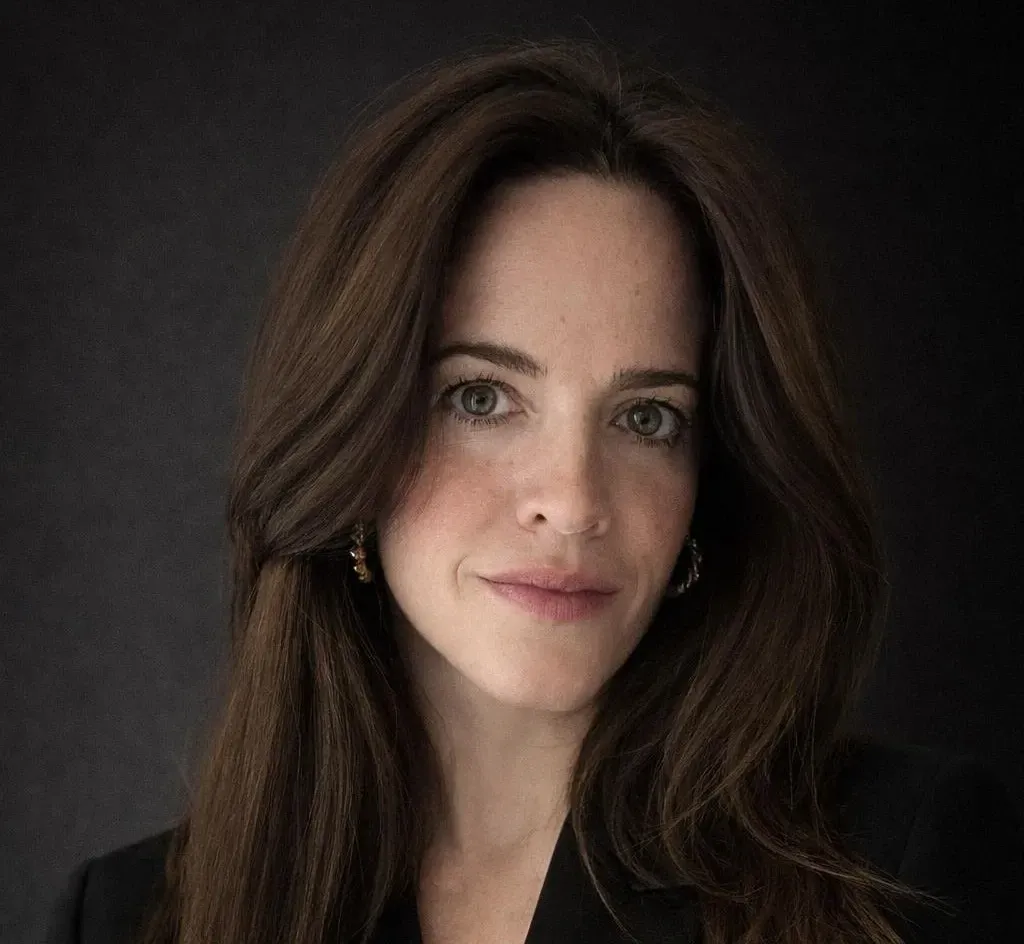 Retrato de una persona con cabello largo castaño, que lleva pequeños pendientes