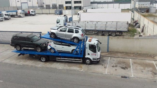 Un camión transportador de automóviles transporta cuatro vehículos en un estacionamiento.