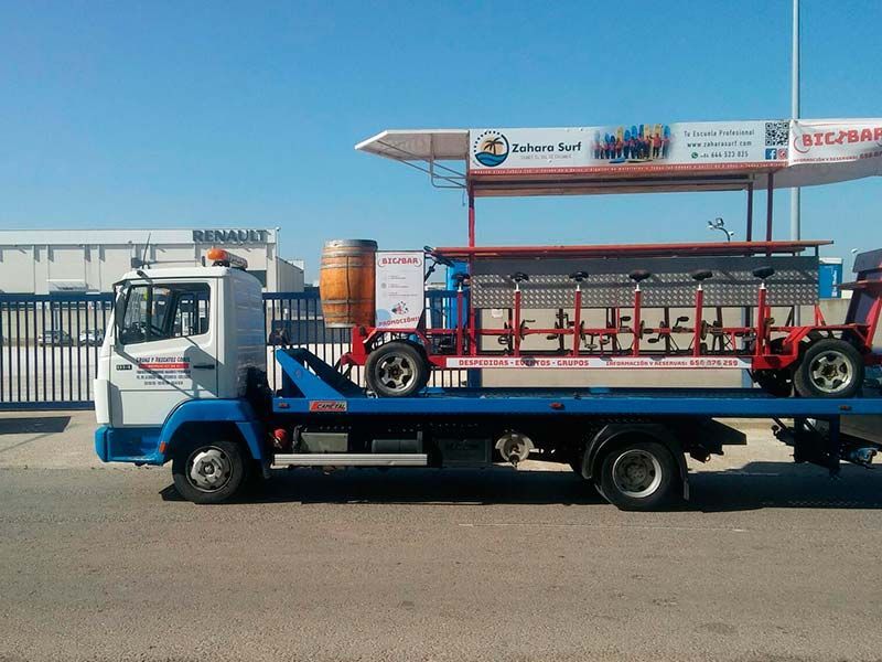 Bicicleta cervecera en un remolque de camión, lista para transportar. Cielo azul y el edificio Renault al fondo.