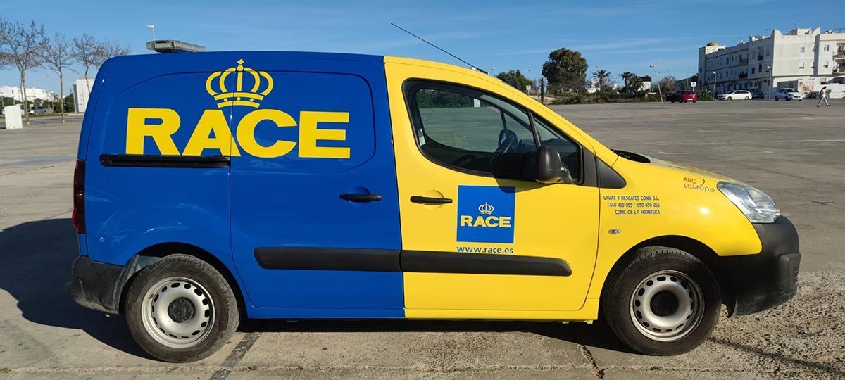 Furgoneta de servicio RACE azul y amarilla estacionada afuera en un día soleado.