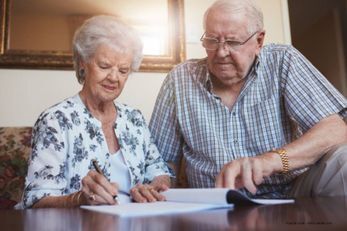 Zwei ältere Personen unterschreiben ein Dokument