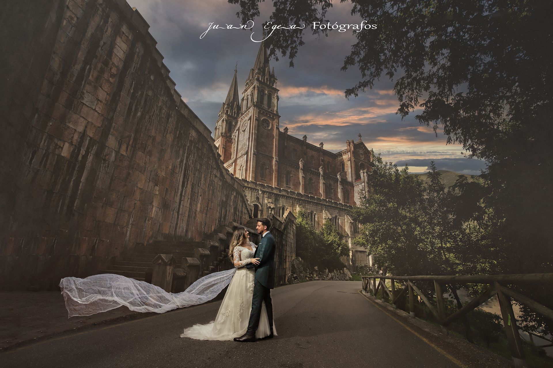 Pareja abrazándose en un camino, un vestido de novia y una catedral al fondo, bajo un cielo nublado.