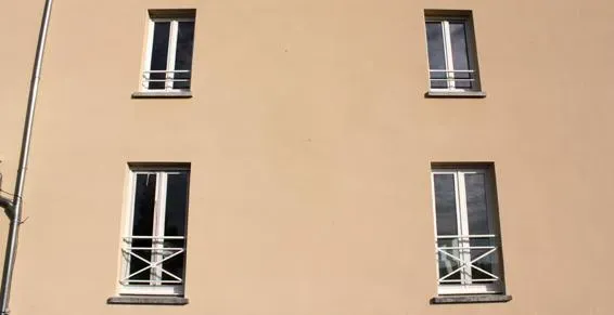 Quatre fenêtres blanches sur une façade neutre