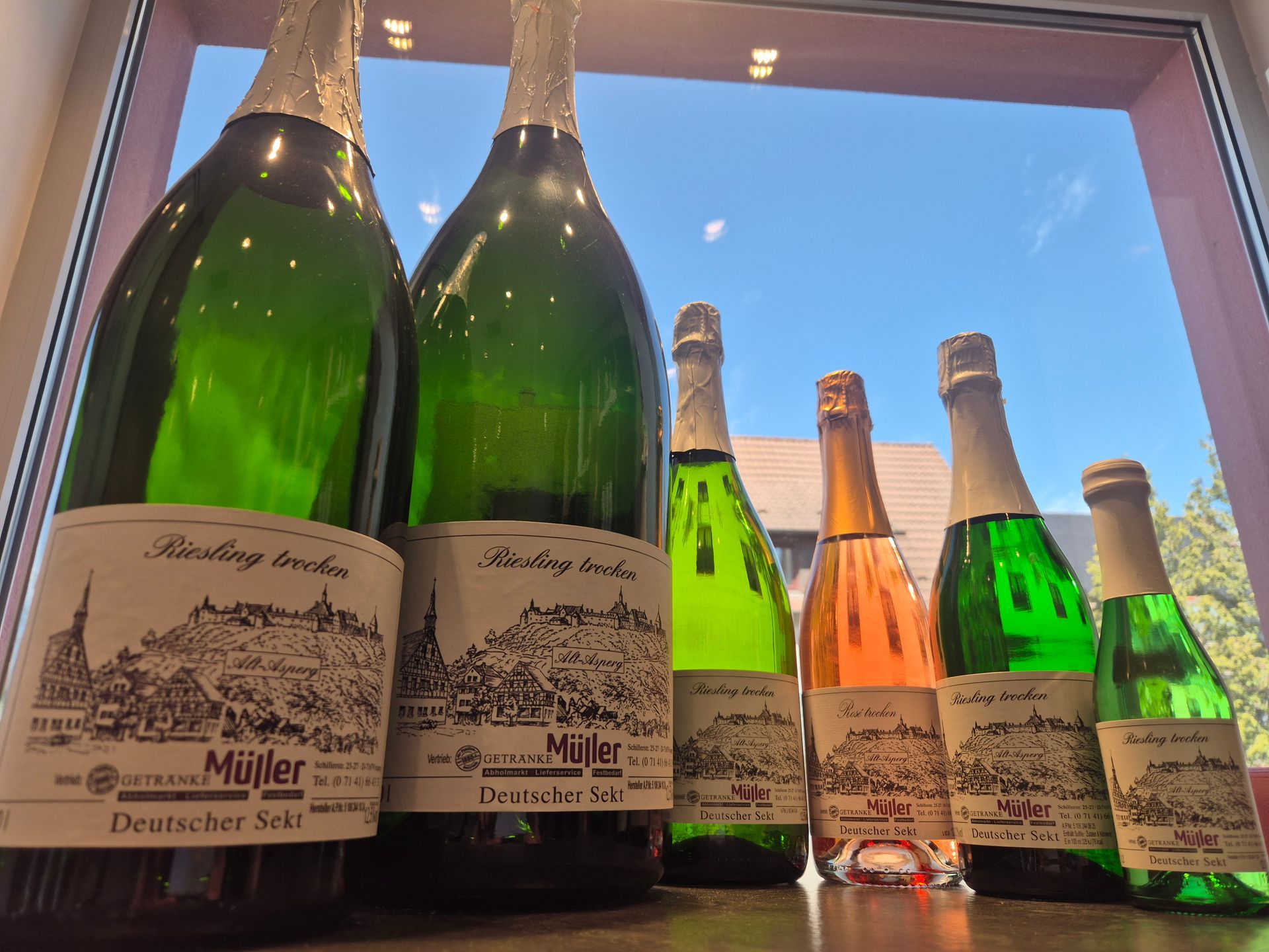 Champagnerflaschen auf dem Fensterbrett, draußen Himmel und Bäume.