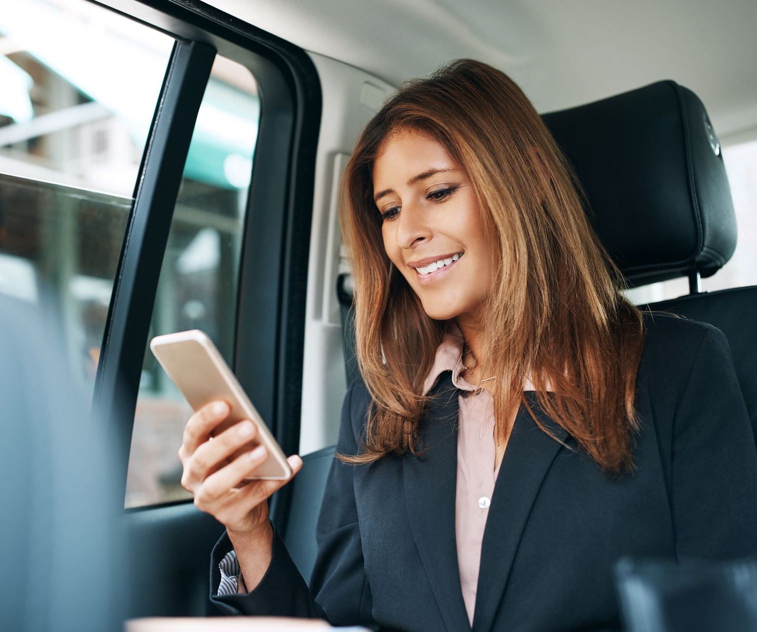 Une femme d'affaires dans un taxi qui consulte son smartphone.
