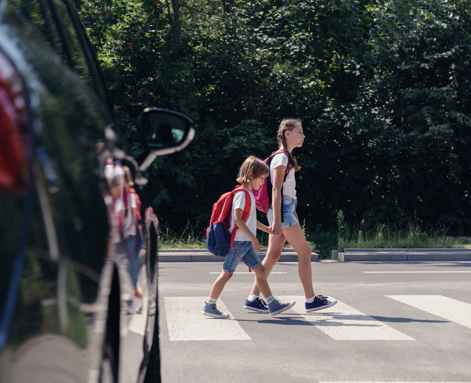 Des enfants avec un sac à dos qui traversent un passage piéton.