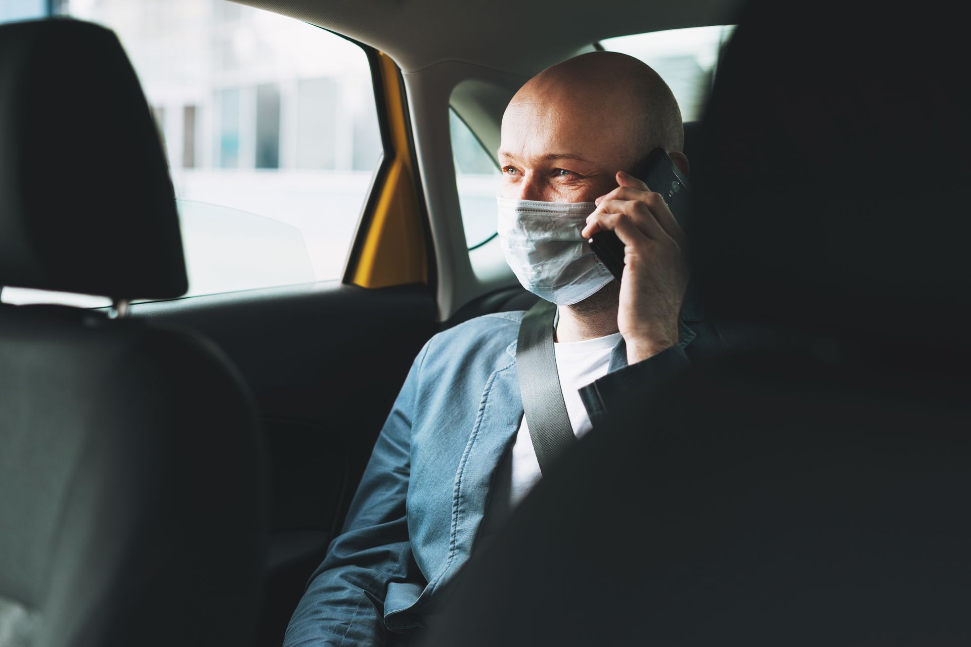 Une personne chauve, portant un masque chirurgical, au téléphone.
