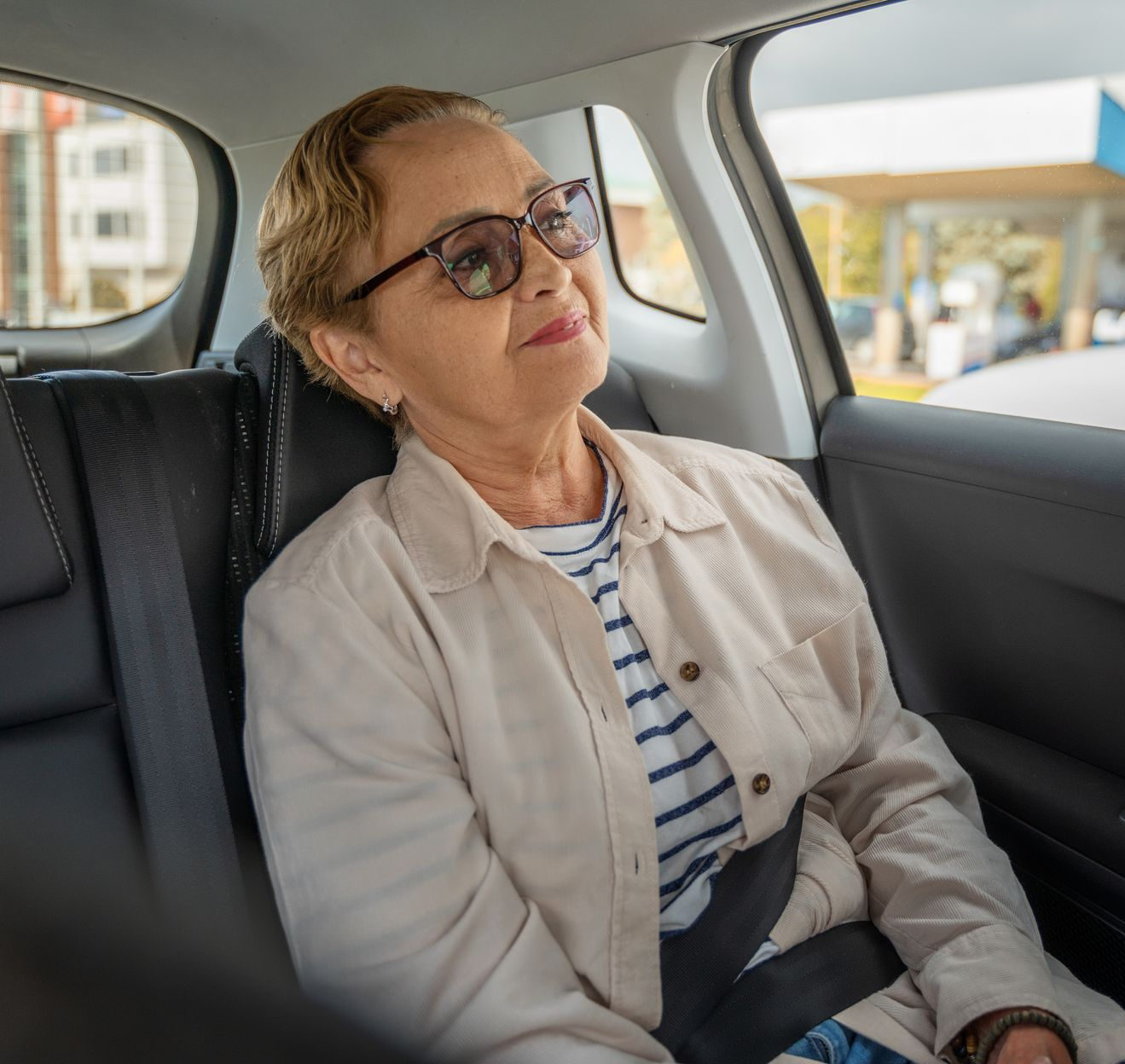 Une femme âgée assise dans un taxi.