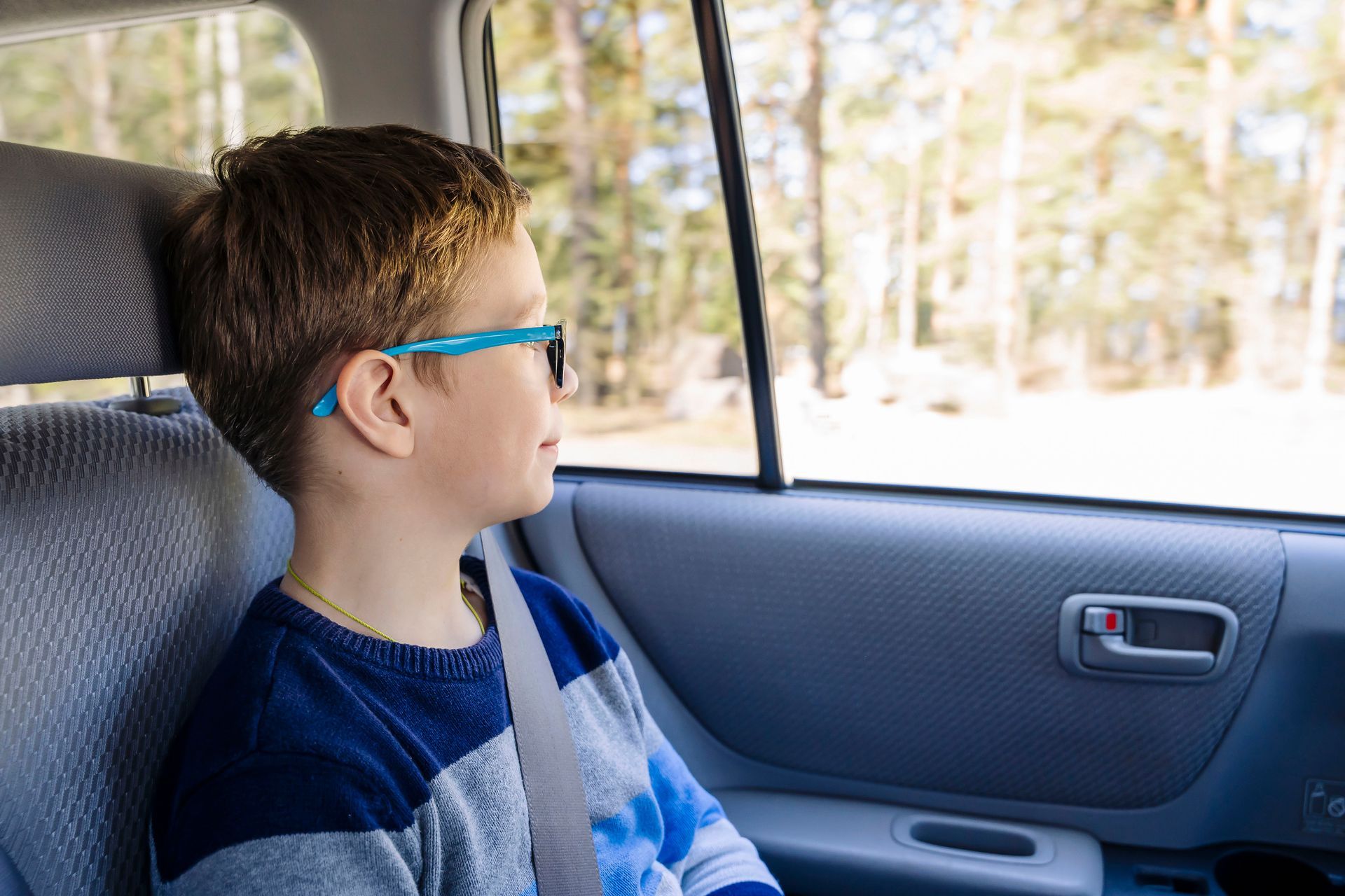 Un petit garçon dans une voiture qui regarde par la fenêtre.
