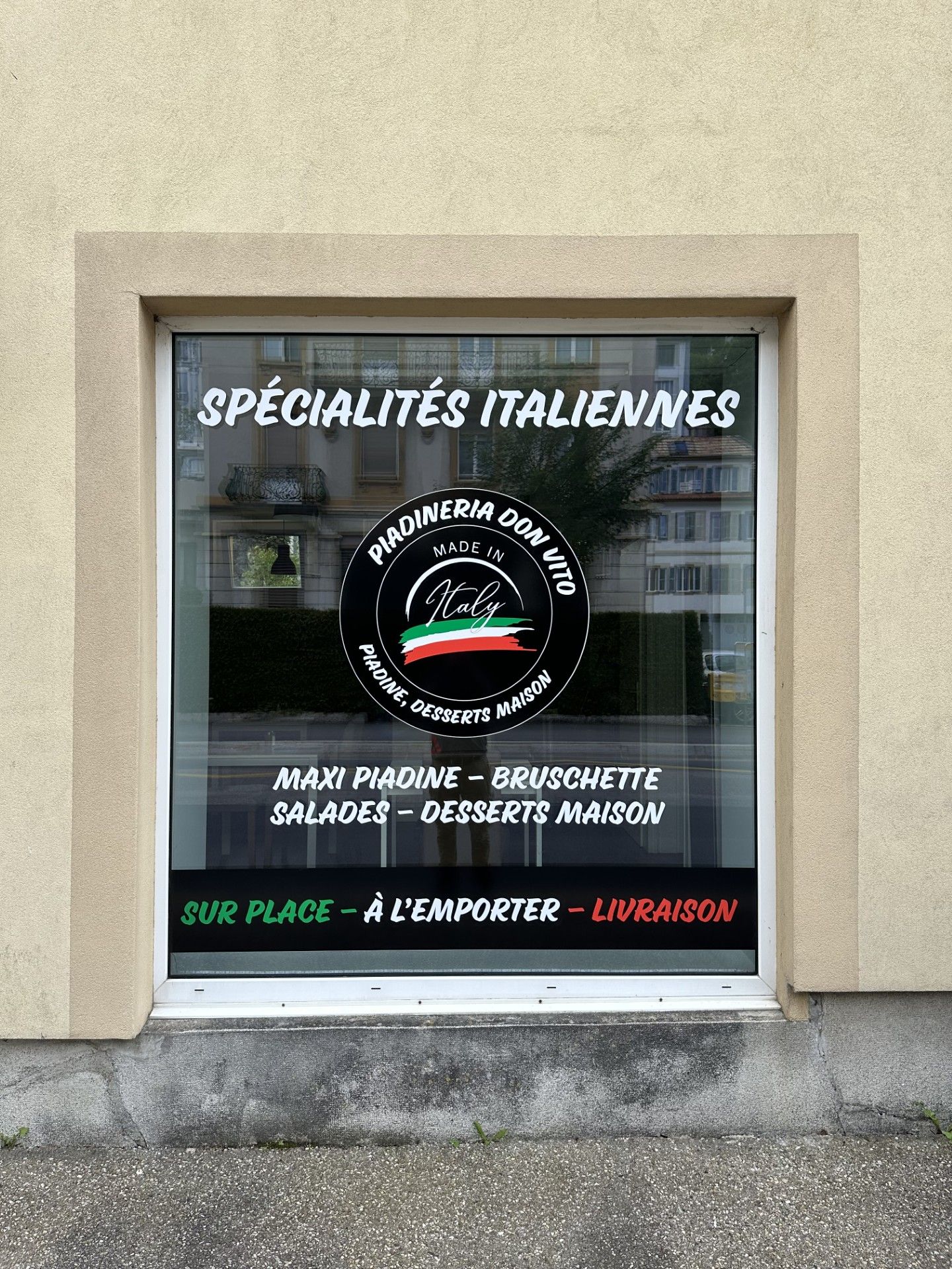 Une fenêtre avec un panneau indiquant spécialités italiennes.