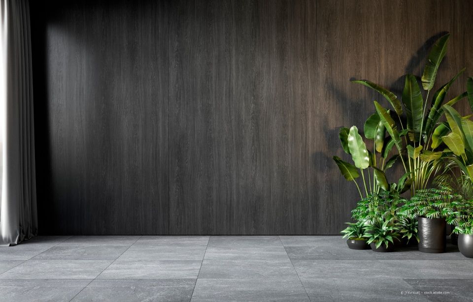 Person, die eine orangefarbene Wand mit einer Farbrolle streicht und dabei teilweise eine weiße Grundierung überdeckt.