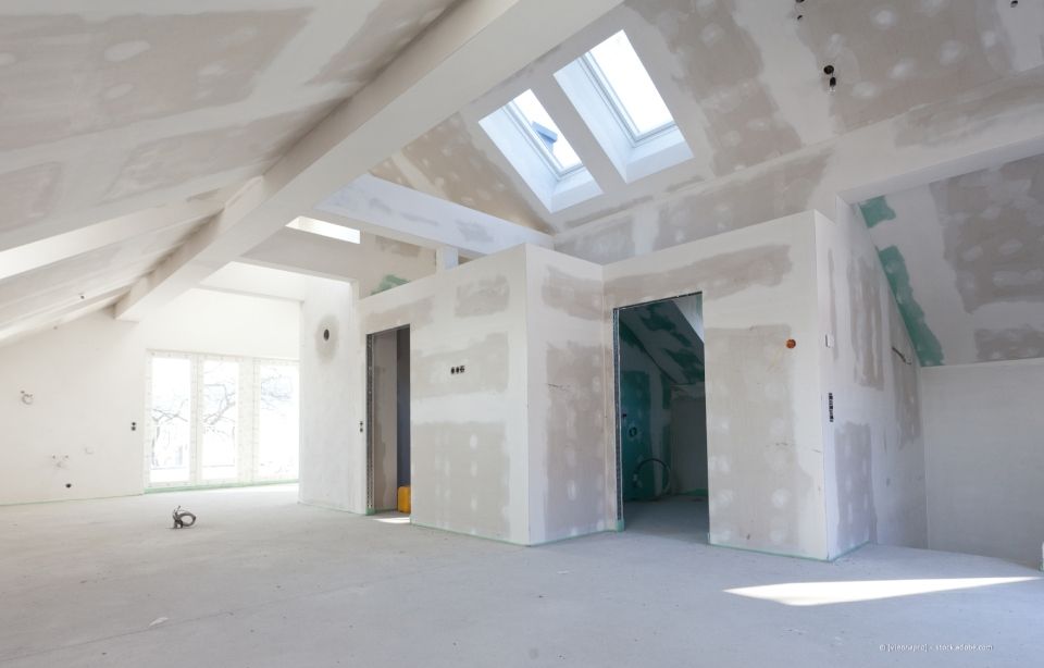 Innenausbau im Gange; Trockenbauinstallation, unfertige Wände, Fenster, blanke Böden.