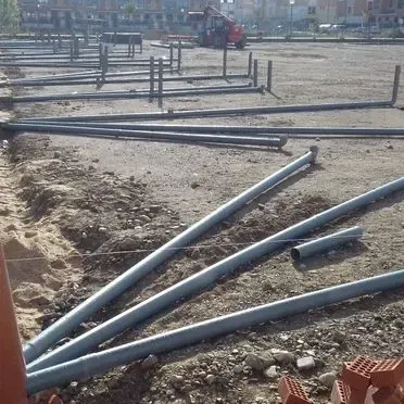 Un montón de tuberías están tiradas en el suelo en un sitio de construcción.