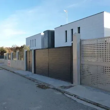 Una hilera de casas con una valla a lo largo del costado de la carretera.