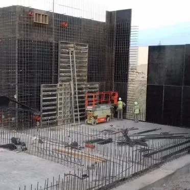 Un grupo de trabajadores de la construcción está parado frente a un edificio en construcción.
