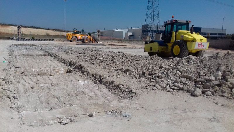 Un tractor amarillo conduce por un campo de tierra.