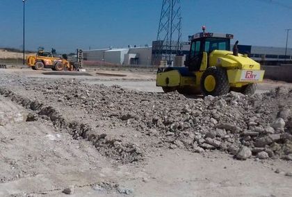Un tractor amarillo conduce por un campo de tierra.